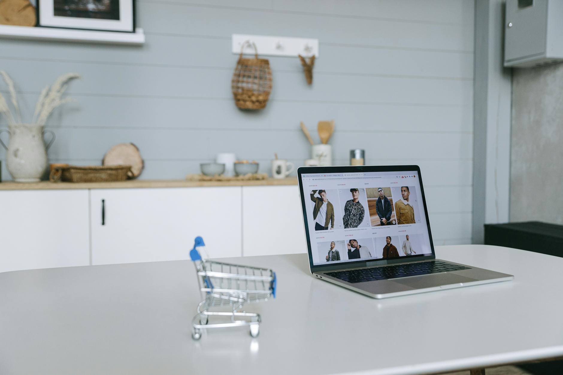 a laptop beside a miniature shopping cart